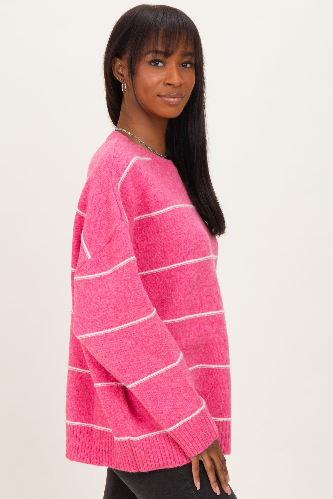 woman wearing a pink striped sweater with a relaxed fit and long sleeves
