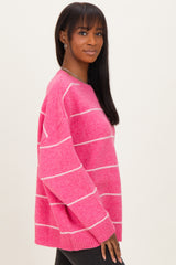 woman wearing a pink striped sweater with a relaxed fit and long sleeves