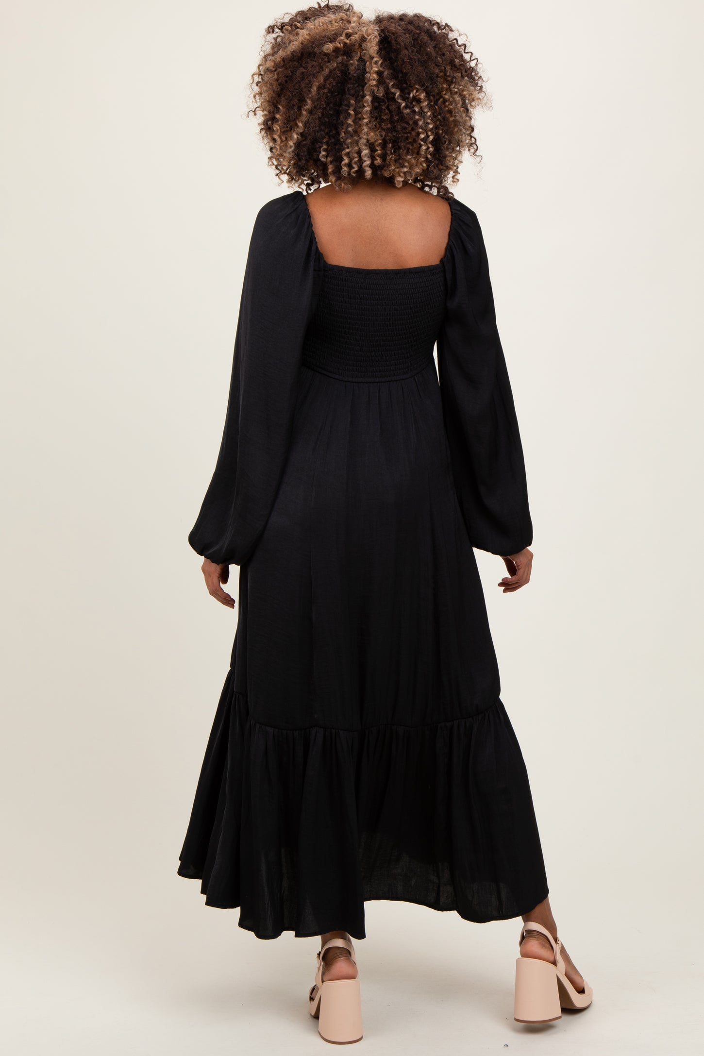 woman wearing a black long sleeve maternity dress with a smocked bodice and tiered skirt from the back