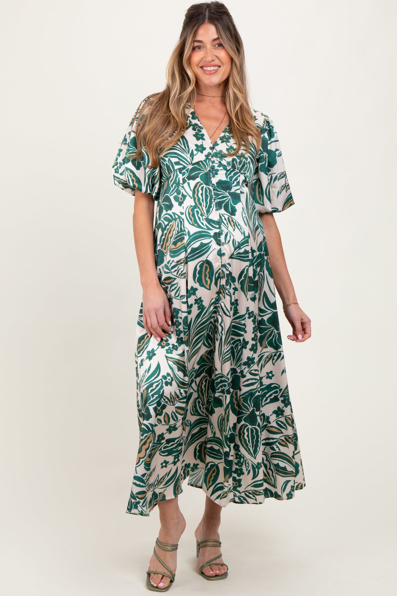 woman wearing a green floral maternity maxi dress with short sleeves and a v-neck, showcasing her baby bump