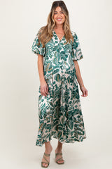 woman wearing a green floral maternity maxi dress with short sleeves and a v-neck, showcasing her baby bump