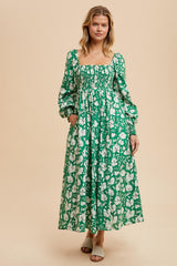 woman wearing a green floral maxi dress with puff sleeves and a square neckline, standing against a neutral background