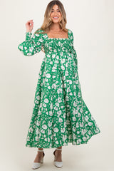 woman wearing a green floral maternity dress with puff sleeves and a smocked bodice, showcasing her baby bump