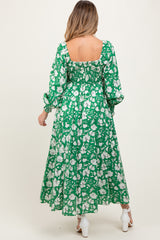 woman wearing a green floral maternity dress with a smocked back and long sleeves, showcasing a flowing skirt