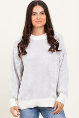 woman wearing a light gray striped oversized sweater with a ribbed texture and white cuffs
