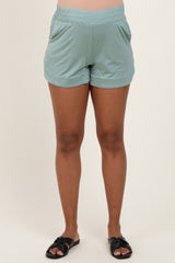woman wearing light green maternity shorts with an elastic waistband and pockets