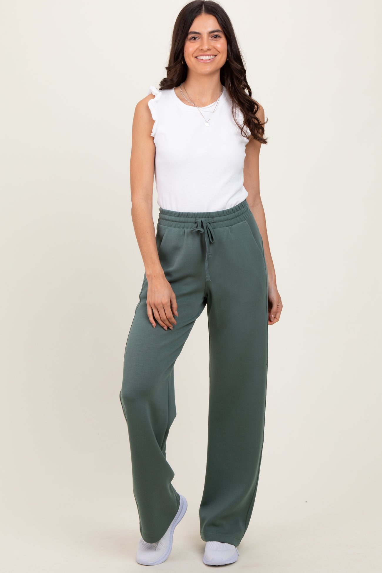 woman wearing a white sleeveless top and green drawstring wide-leg pants