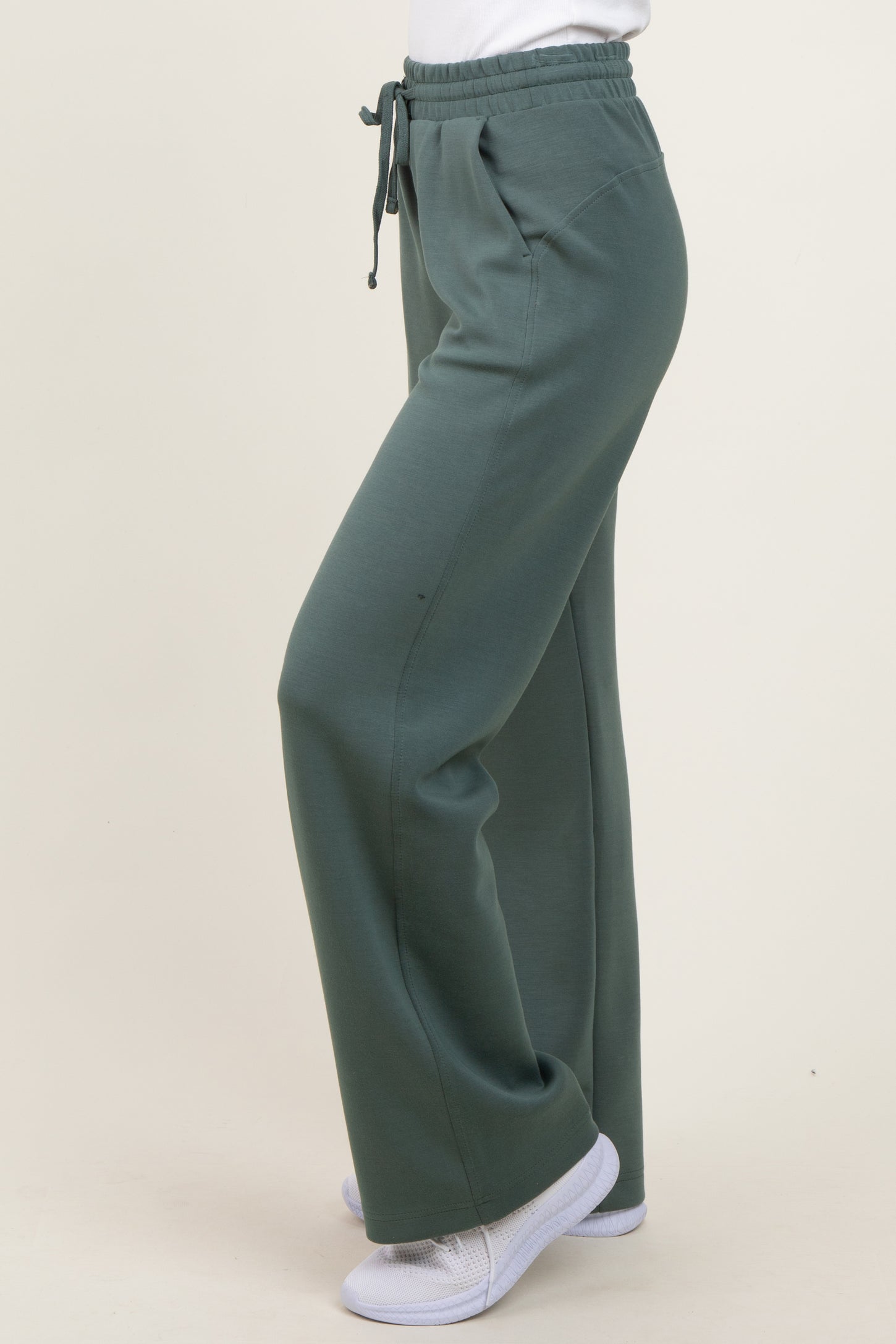 woman wearing green elastic waist sweatpants with a relaxed fit and side pockets