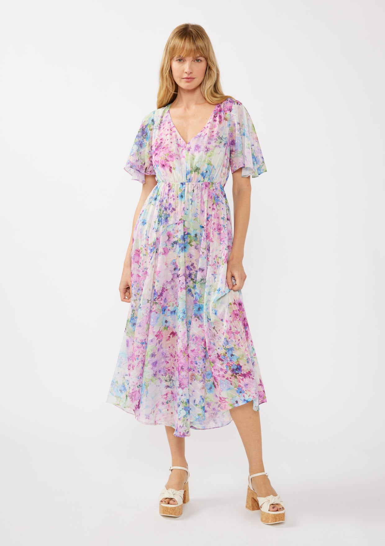 woman wearing a flowing floral midi dress with short sleeves and a v-neckline, standing against a white background