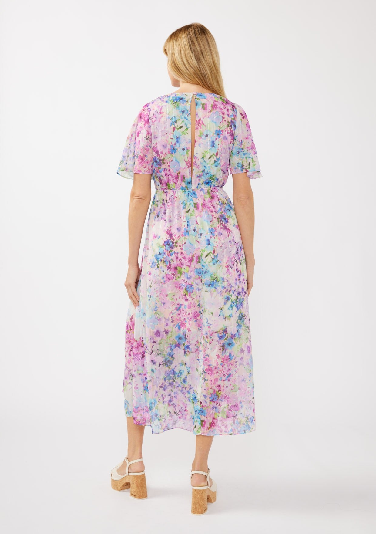 woman wearing a floral print maxi dress with short sleeves and a tie at the waist, showing a slight back opening
