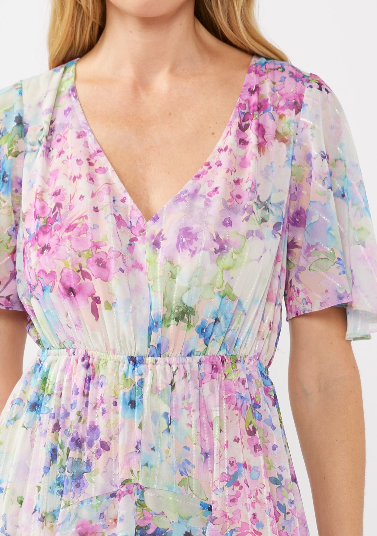 woman wearing a floral print dress in pastel colors with a deep v-neck and flutter sleeves