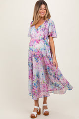 woman wearing a pastel floral print maternity dress with flutter sleeves and a flowy skirt, highlighting her baby bump