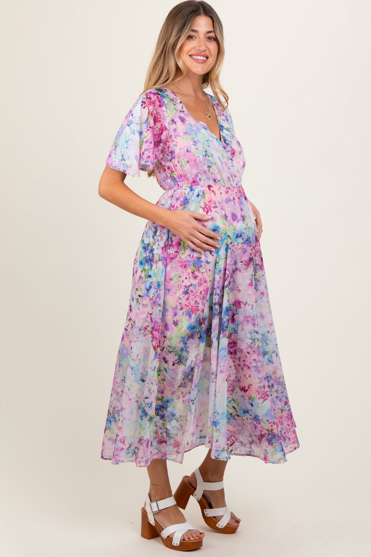woman wearing a floral maternity dress with flutter sleeves and a baby bump visible