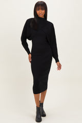 woman wearing a black long sleeve fitted midi dress with a textured overlay and ankle boots