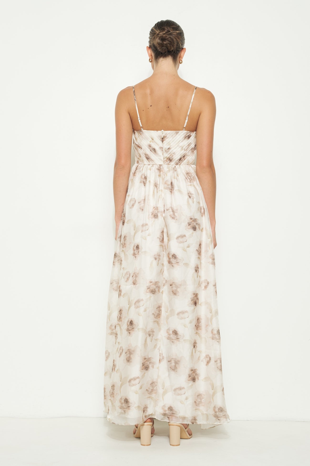 woman wearing a back view of a floral maxi dress with thin straps and a flowing silhouette