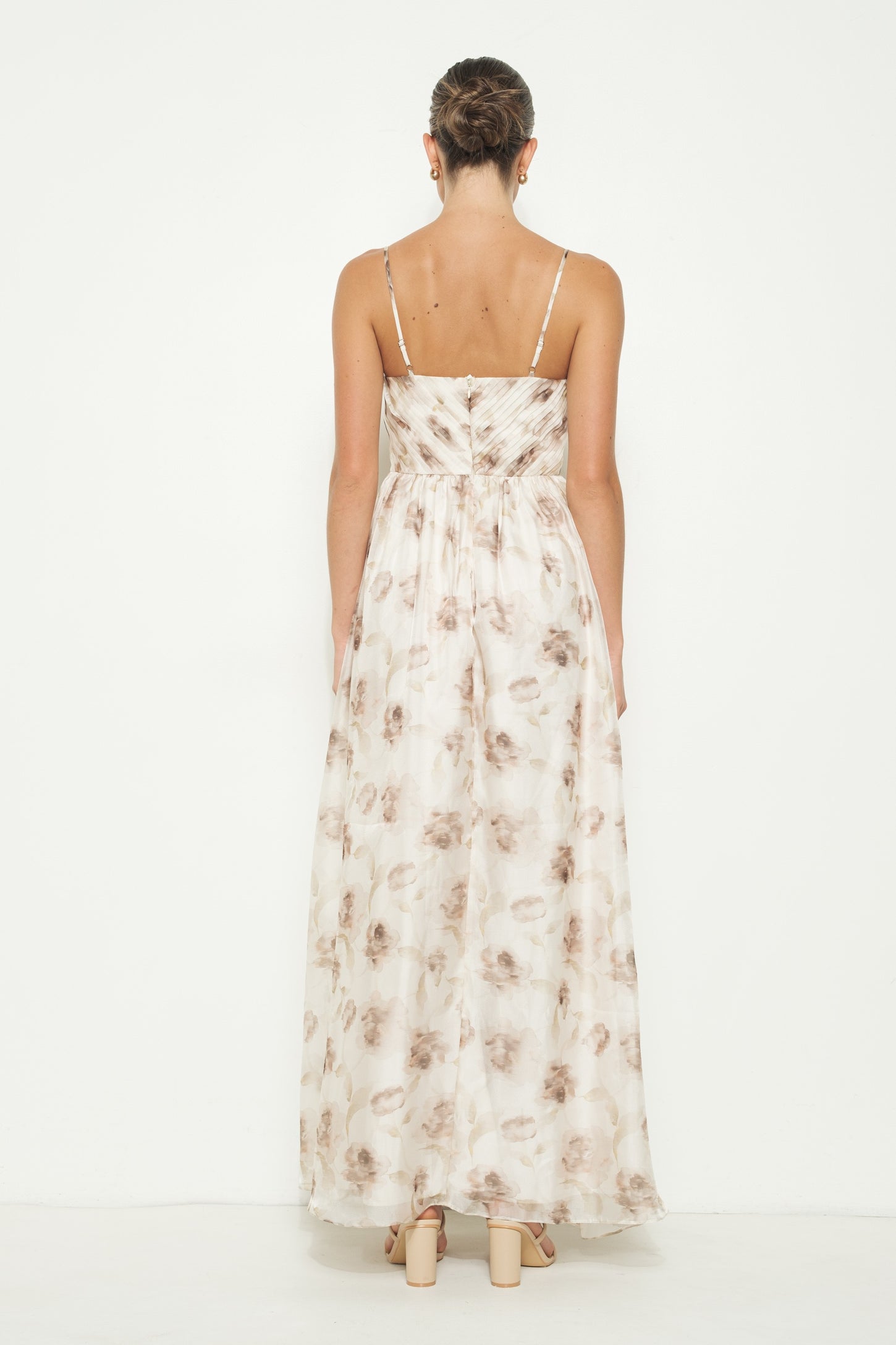woman wearing a back view of a floral maxi dress with thin straps and a flowing silhouette