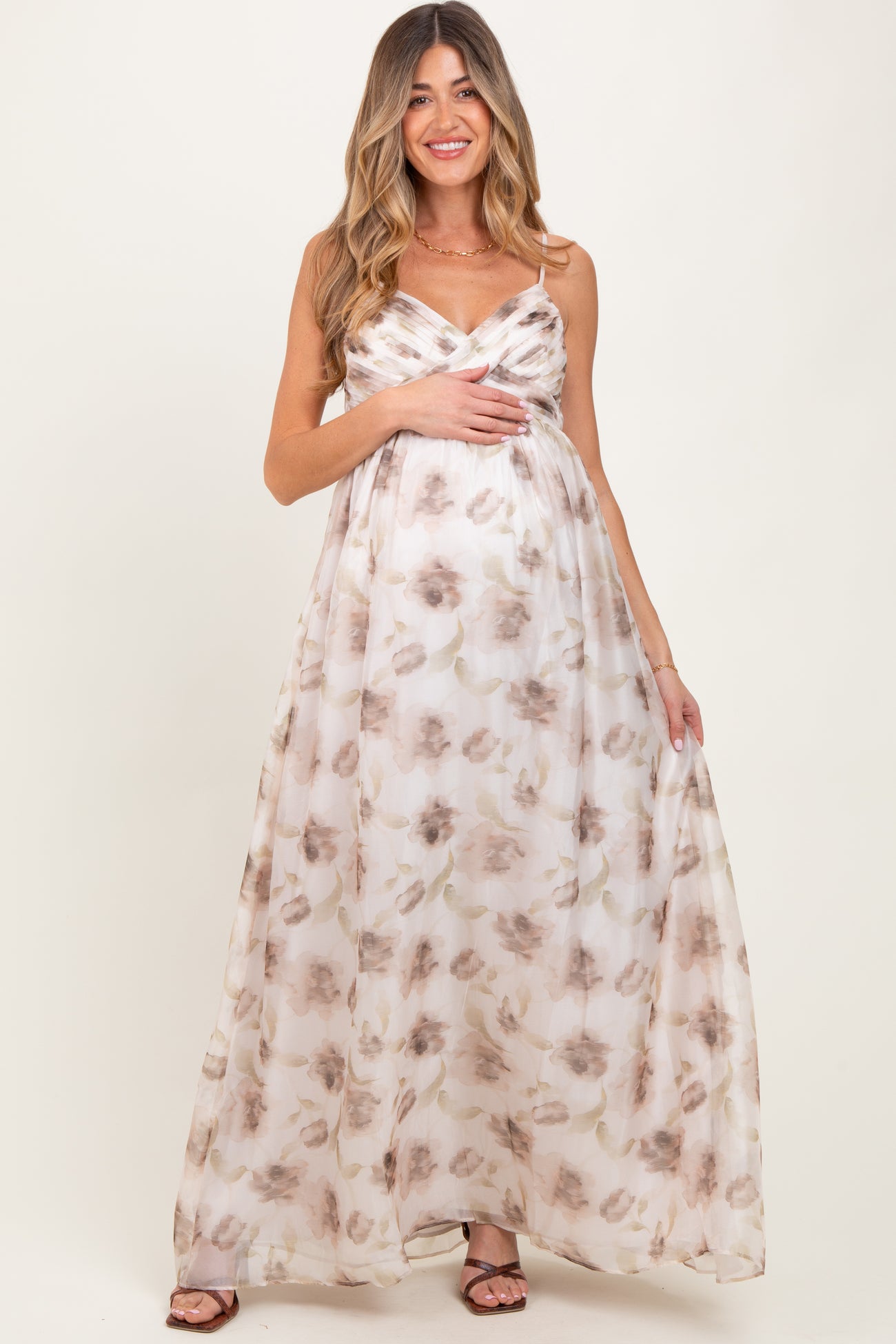 woman wearing a floral print maternity maxi dress with a gathered bodice and holding her baby bump