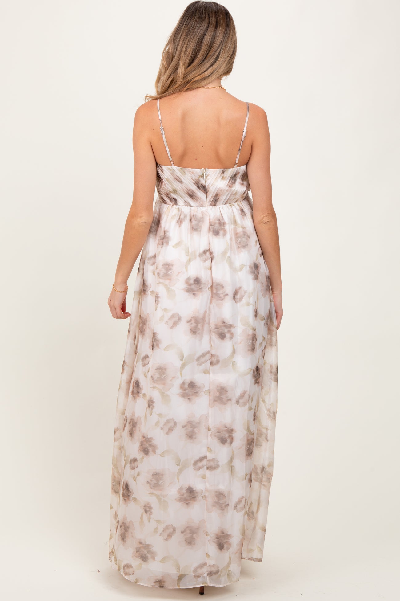 woman wearing a floral maxi maternity dress with adjustable straps and a flowing design from the back