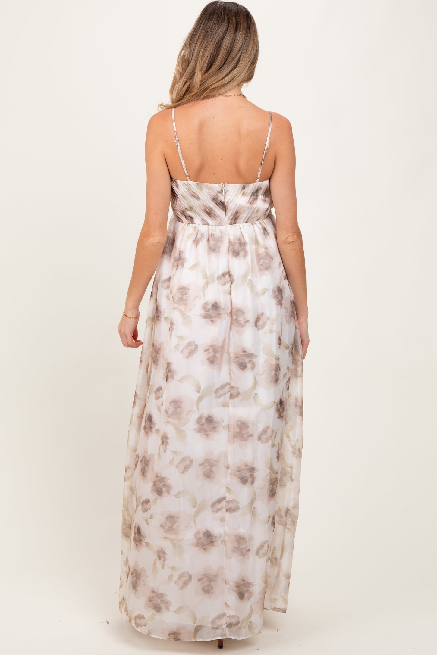 woman wearing a floral maxi maternity dress with adjustable straps and a flowing design from the back