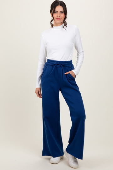 woman wearing a white long sleeve top and navy blue wide-leg pants with an elastic waistband and side pockets