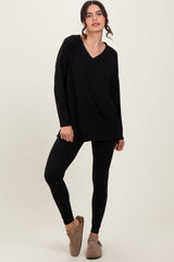 woman wearing a black long sleeve v-neck top and black leggings, with brown slip-on shoes