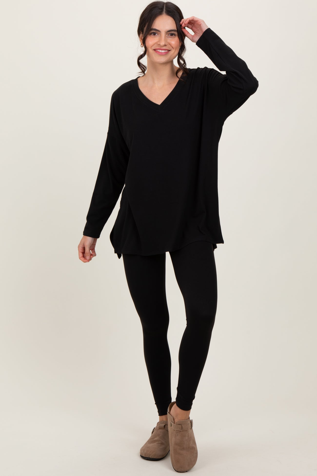 woman wearing a black long sleeve v-neck top paired with black leggings and brown ankle boots