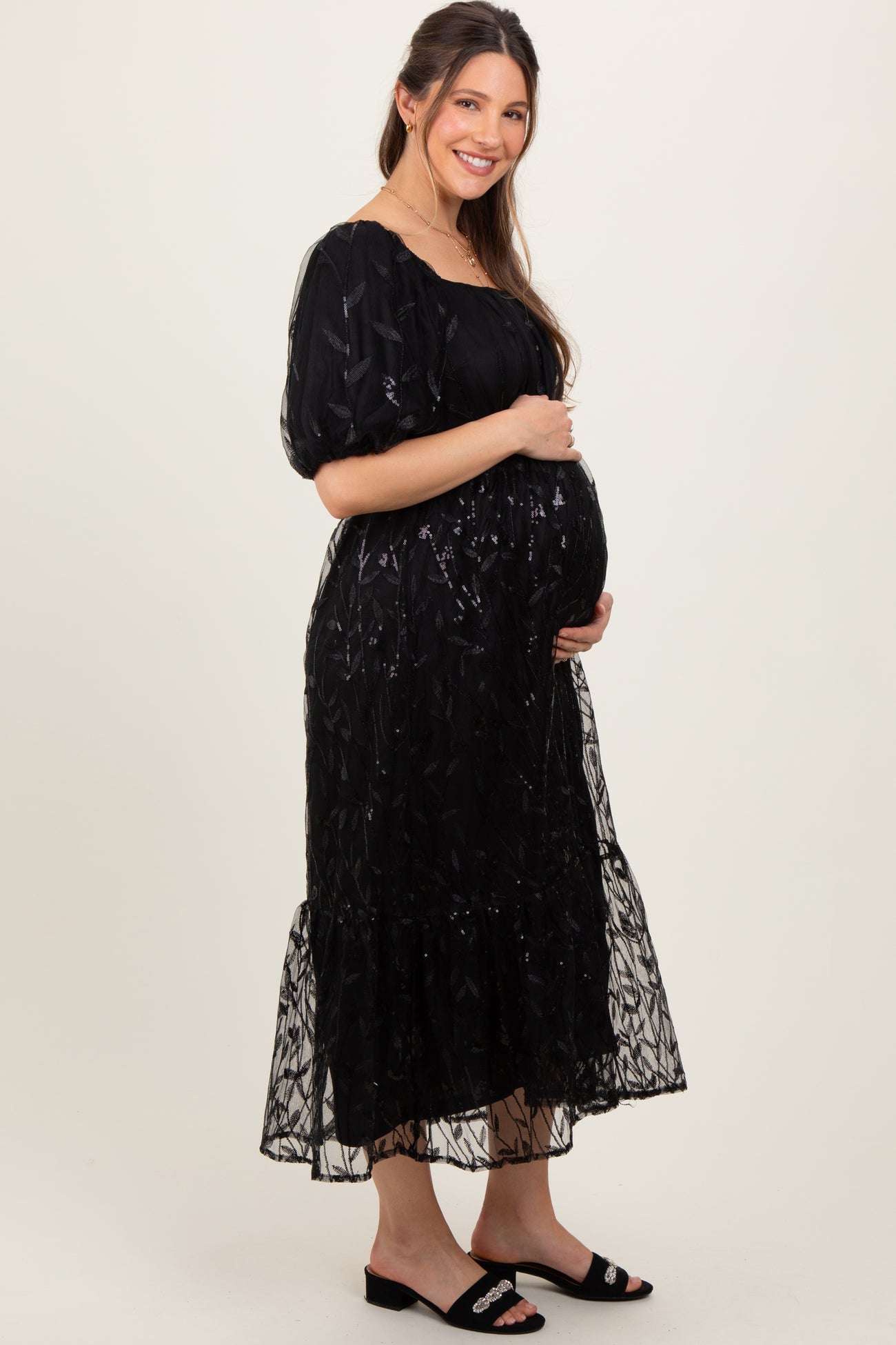 woman wearing a black embroidered maternity dress with puff sleeves and a baby bump