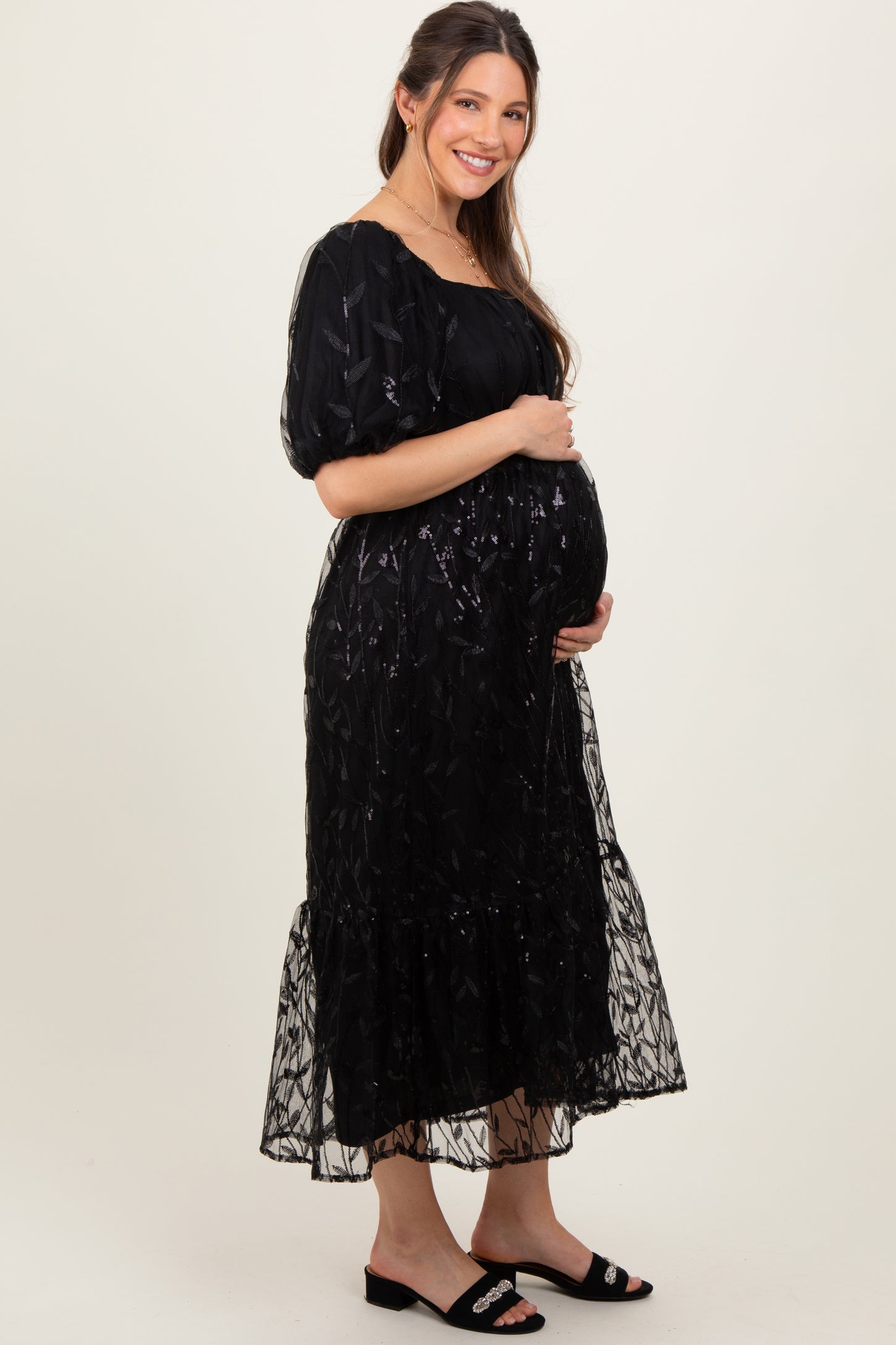 woman wearing a black embroidered maternity dress with puff sleeves and a baby bump