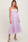 woman wearing a lilac maternity dress with embroidered bodice and ruffled hem, showing her baby bump