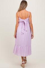 woman wearing a lavender maternity dress with a back bow detail and a ruffled hem