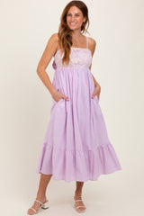 woman wearing a lavender sleeveless maxi dress with lace bodice and ruffled hem, posing with pockets