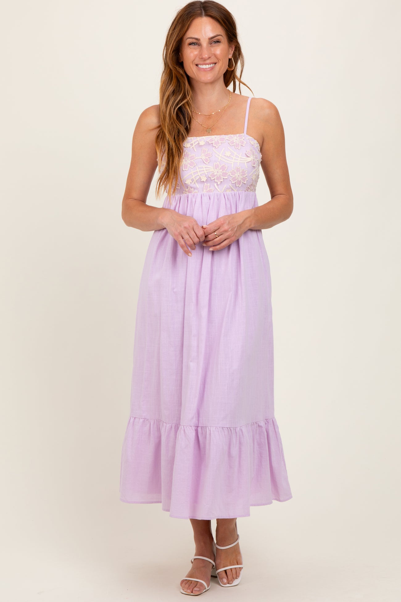 woman wearing a lavender maxi dress with a lace bodice and ruffled hem, posing and smiling