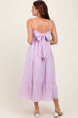 woman wearing a lavender sleeveless dress with a back bow detail and tiered hem