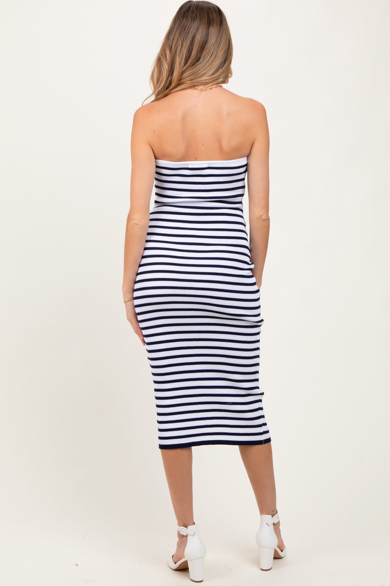 woman wearing a navy and white striped maternity dress that is fitted and knee-length without sleeves