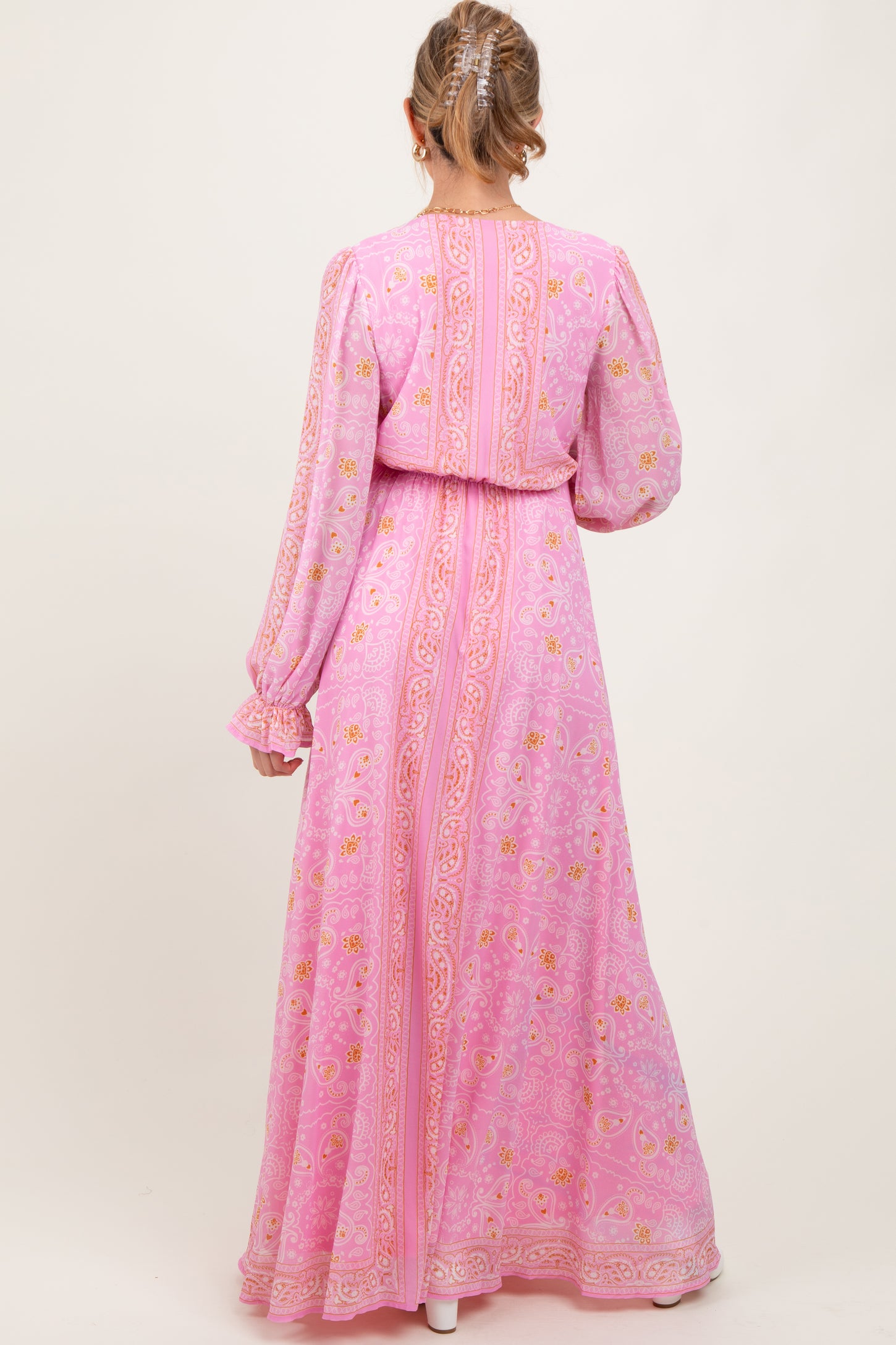 woman wearing a pink floral long sleeve maternity maxi dress with a cinched waist and flowing skirt