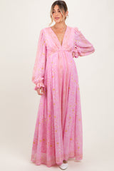woman wearing a pink floral long sleeve maternity dress with an empire waist and flowing skirt, showcasing a baby bump