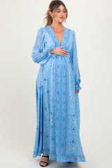 woman wearing a light blue paisley print maternity maxi dress and holding her baby bump