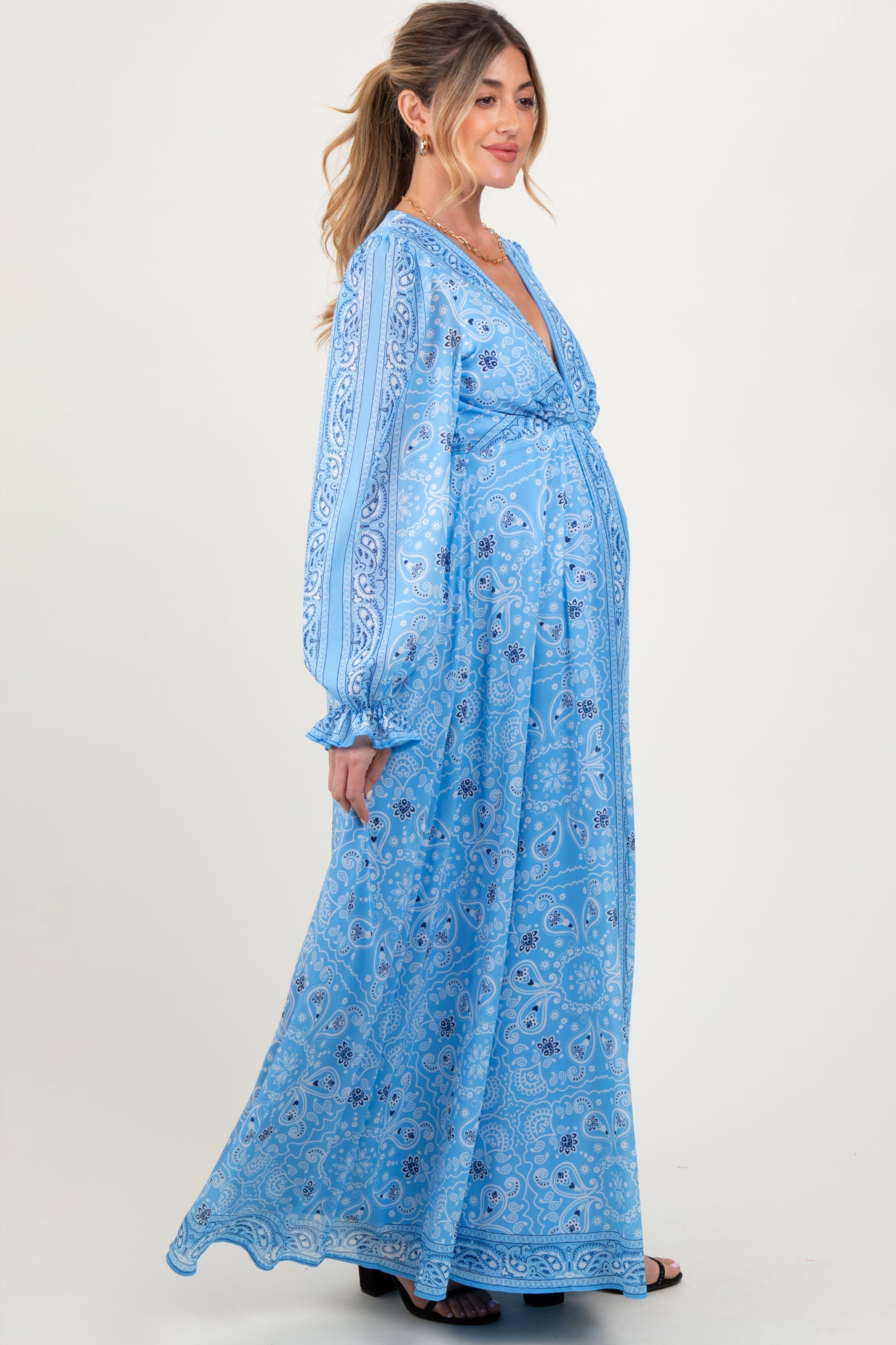 woman wearing a light blue patterned maternity maxi dress with long sleeves and a visible baby bump