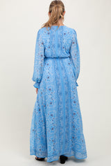 woman wearing a long sleeve blue patterned maternity maxi dress with a tie waist from the back