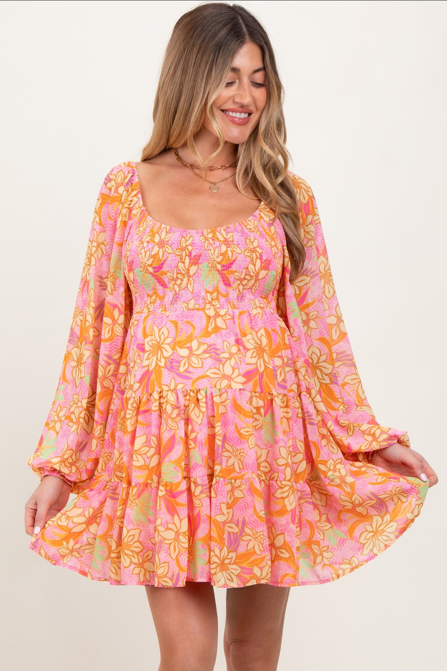 woman wearing a pink floral maternity dress with long sleeves and a flared skirt