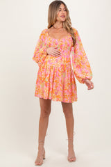 woman wearing a pink floral maternity dress with puff sleeves and a gathered waist, holding her baby bump