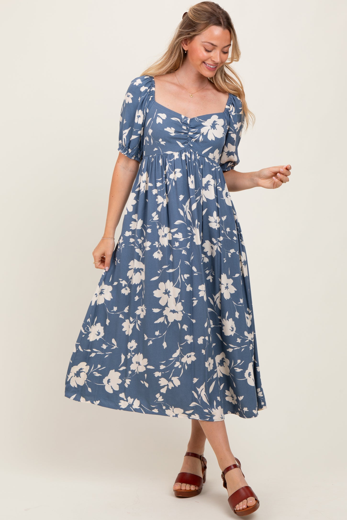 woman wearing a blue floral print midi dress with short puff sleeves and a square neckline