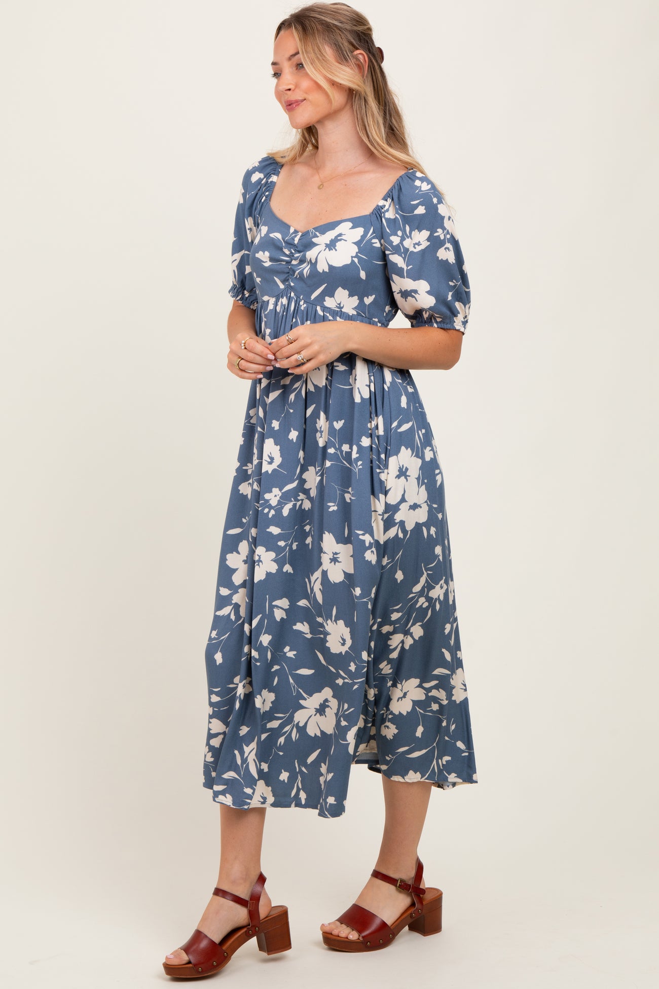 woman wearing a blue floral mid-length dress with puff sleeves and a square neckline