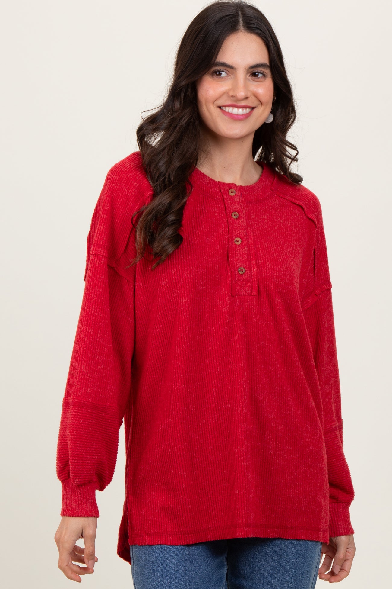 woman wearing a red long sleeve pullover top with buttons and loose fit, smiling at the camera