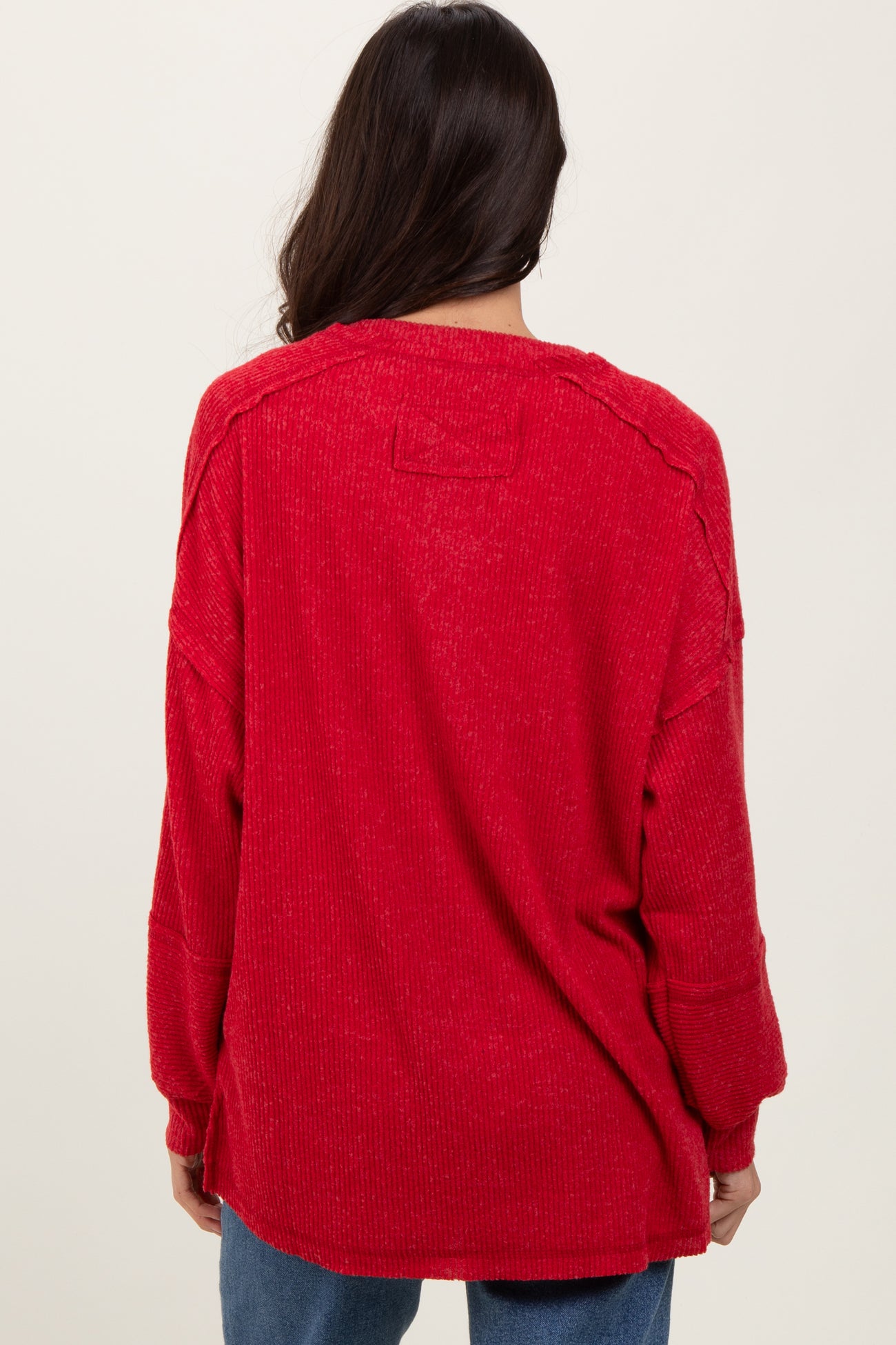 woman wearing a red oversized sweater with a relaxed fit and dropped shoulder seams, view from the back