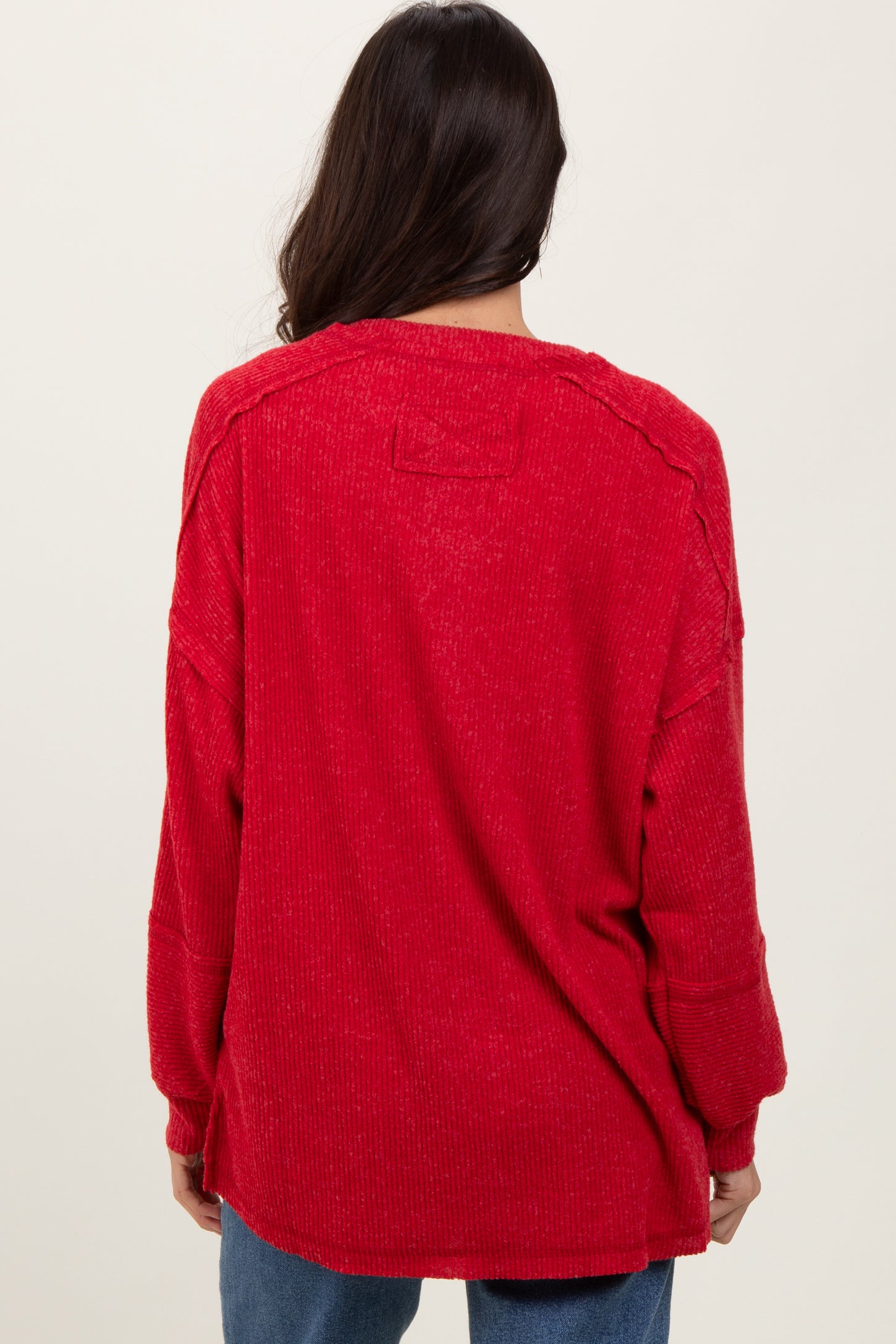 woman wearing a red oversized sweater with a relaxed fit and dropped shoulder seams, view from the back