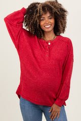 woman wearing a red maternity long sleeve button-up top with a relaxed fit and a baby bump visible