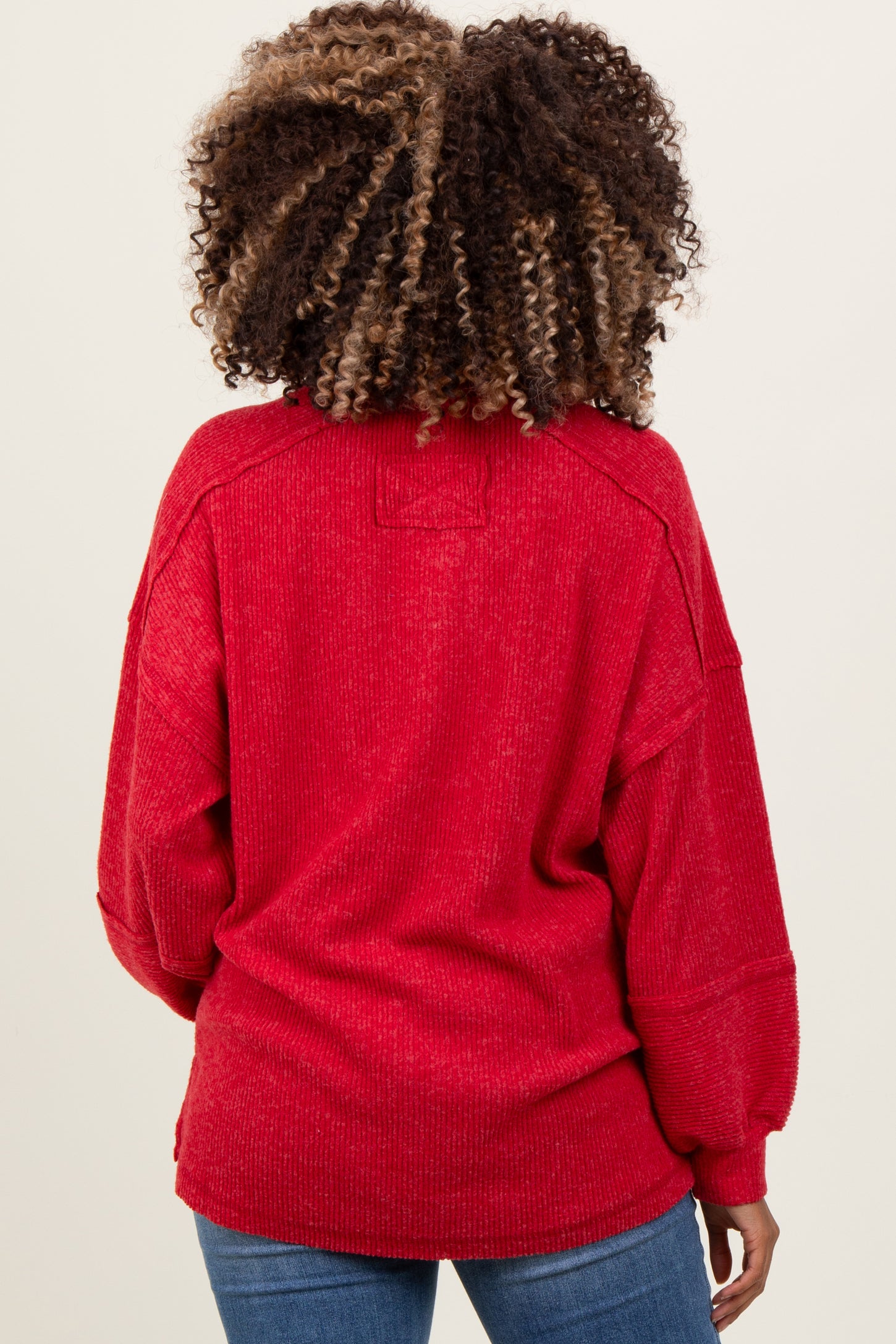 woman wearing a red oversized maternity sweater with a relaxed fit and ribbed details, shown from the back