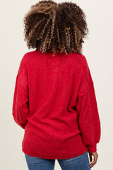 woman wearing a red oversized maternity sweater with a relaxed fit and ribbed details, shown from the back