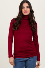 woman wearing a burgundy long sleeve turtleneck top with a fitted silhouette and soft fabric